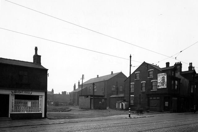 This photo shows an Air Raid Wardens Post on Driver Street viewed from Wellington Road, in the centre of the photograph. To the left is 'Bettys Beauty Parlour'. On the right is an empty shop with houses. On the side of the house is an advertisement for 'Bile Beans'. Tramlines and tram cables can be seen with blackout paint on the poles and also the kerbs. Pictured in September 1945.