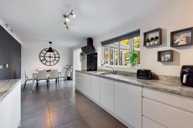 The kitchen is part-tiled with ceiling spotlights, an integrated fridge, freezer, dishwasher, electric double oven and hob with an extractor fan