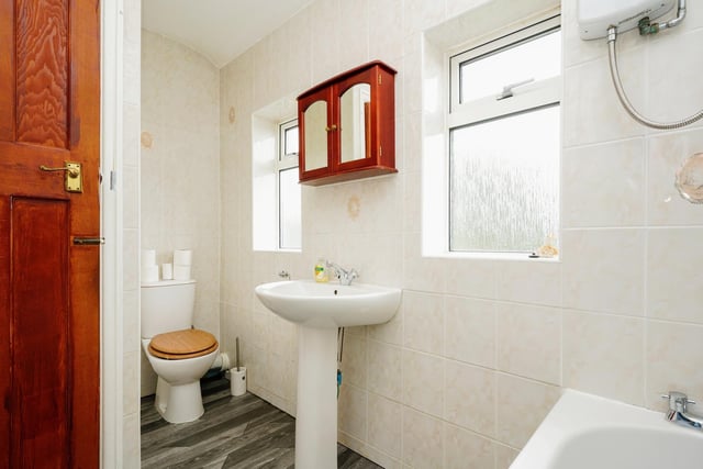 The house bathroom is situated near the three bedrooms, and has cream tiling lining the walls plus a bath shower unit.