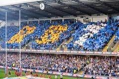 Fans in AMT Headingley's East Stand use flags to display Rob Burrow's initials and squyad number before Rhinos' win agianst Leigh.