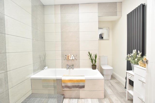 The main bathroom has a modern four-piece suite in white which incorporates ceramic tiled walls, ceramic tiled floor, a wall mounted vertical radiator, ceiling spotlights and a skylight window.