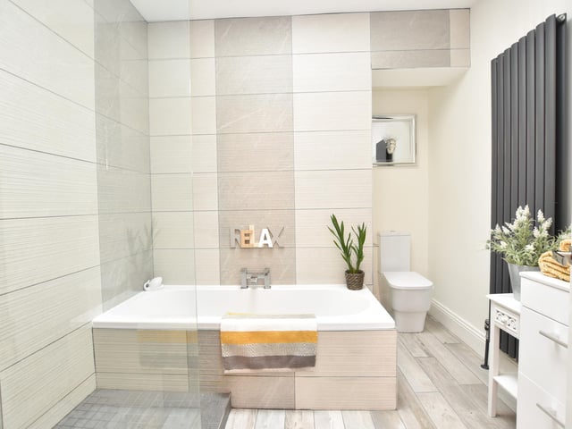 The main bathroom has a modern four-piece suite in white which incorporates ceramic tiled walls, ceramic tiled floor, a wall mounted vertical radiator, ceiling spotlights and a skylight window.