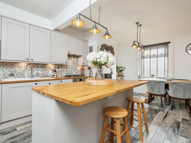 The kitchen features a breakfast island, electric oven, gas hob and extractor over, fridge, integrated microwave and washing machine.