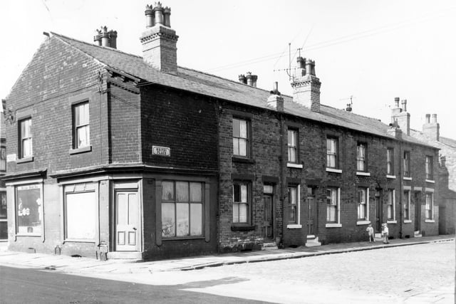 The junction of Roxburgh Street on the left and Whitby Place on the right in August 1964. On the far left at number 24 Roxburgh Street is a grocers while the shop on the right at number 22 is empty. On the right are four back-to-back, double fronted terraced houses with a yard on the right originally built to house the shared outside toilet. Three young boys are stood outside number 5.