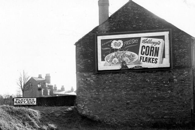 The side of number 407 Harrogate Road with a poster for Kellogg's cornflakes. To the left is an advertisement for Players Navy Cut tobacco and cigarettes. Pictured in February 1952.
