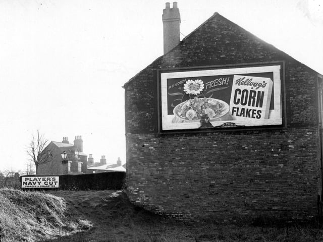 The side of number 407 Harrogate Road with a poster for Kellogg's cornflakes. To the left is an advertisement for Players Navy Cut tobacco and cigarettes. Pictured in February 1952.