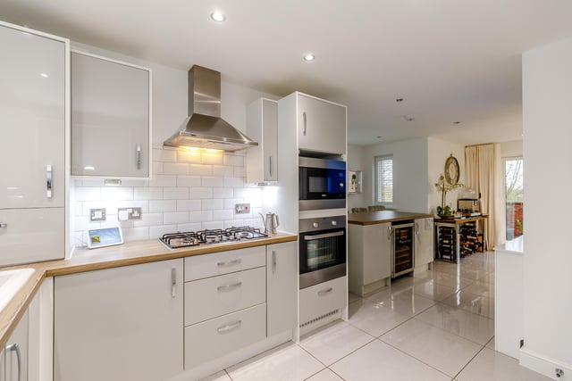 Fitted appliances within the kitchen include an electric oven and built-in microwave, five gas ring hobs and an extractor fan, with a fridge, separate freezer and a dishwasher.