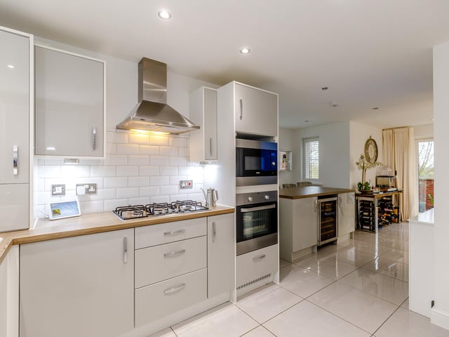 Fitted appliances within the kitchen include an electric oven and built-in microwave, five gas ring hobs and an extractor fan, with a fridge, separate freezer and a dishwasher.
