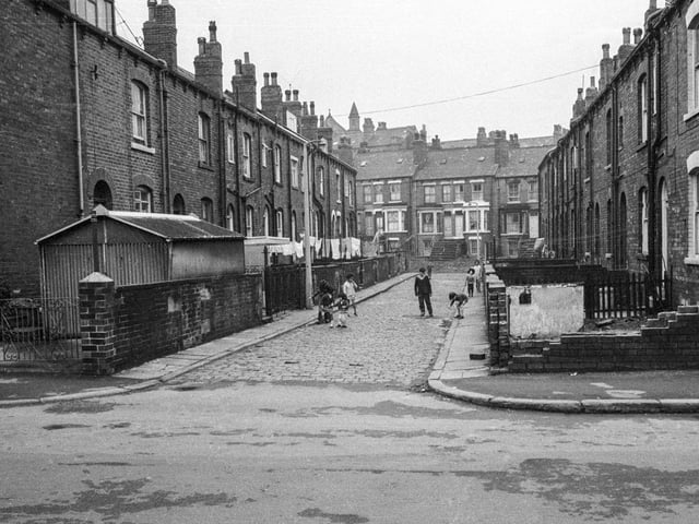 A view looking along Back Gipton Avenue from Gathorne Terrace in 1969. Backs of houses on Gipton Terrace are on the left while on the right are houses which face on to Gipton Avenue. Several children of varying ages are seen playing in the street. Houses running along in the background are on Bankside Street.