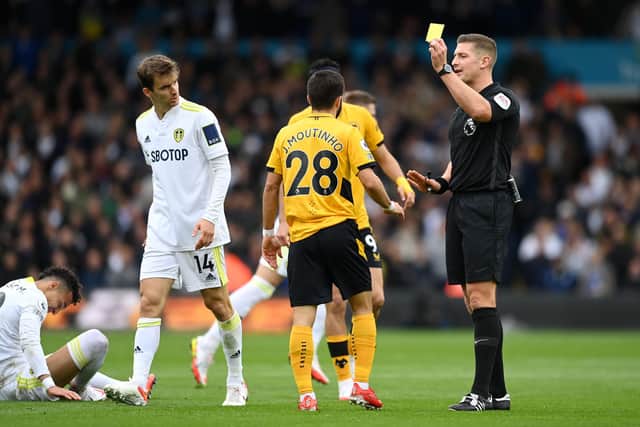 LEEDS, ENGLAND - OCTOBER 23: Match referee, Robert Jones shows a yellow card to Joao Moutinho of Wolverhampton Wanderers during the Premier League match between Leeds United and Wolverhampton Wanderers at Elland Road on October 23, 2021 in Leeds, England. (Photo by Michael Regan/Getty Images)