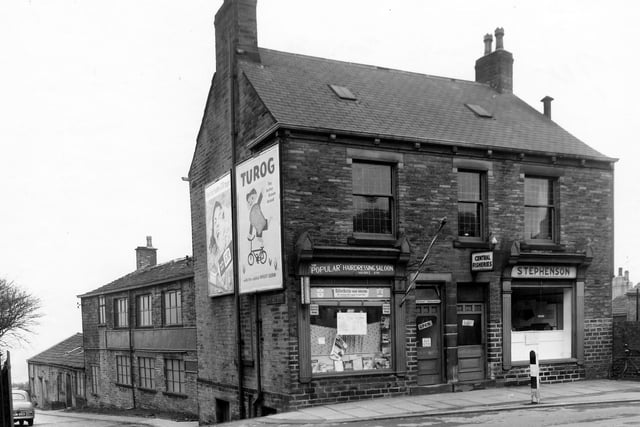 Two shops on  Bramley Town Street in March 1960. To the left is The 'Popular' hairdressing salon run by Maurice Ash displaying a striped Barber's Pole outside. And Central Fisheries run by John W. Stevenson. In the background, left T.H. Wilson Ltd, engineering works can be seen, also known as Aero Metal Works.