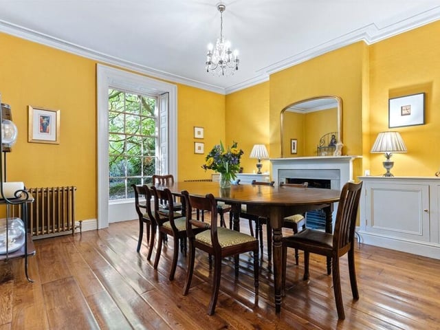 A formal dining room features a gas fire, original shutters and solid oak flooring.