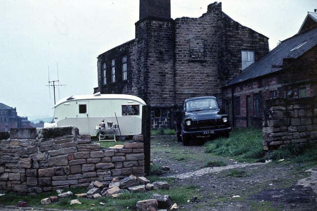 The ruined stoned building of Scholes Bobbin Works on Troy Hill with a view down to Station Road. At one time it produced shuttle bobbins for the weft industry, especially when they were made from wood rather than compressed cardboard. It had been closed for a long time when this image was taken and it seems that the yard was occupied by a travelling family. The flight of steps down to Station Road was closed about 1990 when a survey indicated that nobody used them. The bobbin works once burned down on Wednesday, October 4, 1916.