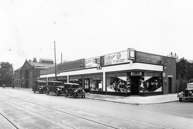June 1934 and in focus is electrical shop Morgan and Waddington on Otley Road. The bus depot can be seen in the background. There are cars parked on the road. Tramlines are shown in the foreground.