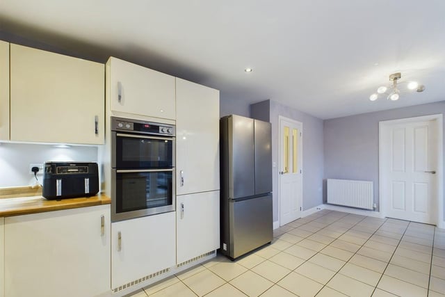 The kitchen features top-notch appliances, including a double electric oven, a 6-ring gas hob, and an integrated dishwasher.