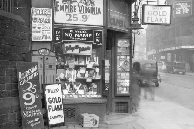 The shop premises of Fred Groves, tobacconist, on New Briggate. A large number of signs for tobacco are in view. Over the shop an electric sign for Essolube oil. Empire Virginia Cigarettes on the window with Players. Pictured in September 1937.