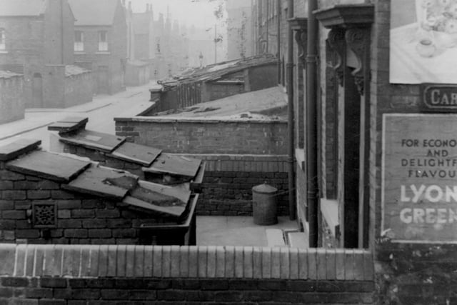 The back of a row of terraced houses down Prince Street pictured in July 1941. The closest house to the photographer is 39 Prince Street owned by Miss Annie Farmery. In this yard is a metal bin. On the side of the house are two billposters and a sign reading 'Carter Road'.