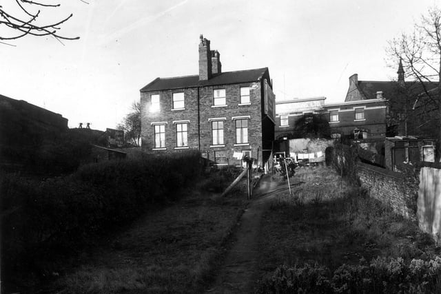 This view from October 1959 looks up long back gardens to the rear of numbers 247 (left) and 245 (right) on Burley Road. The embankment for the Leeds - Harrogate Railway Line is on the left; to the right is Back House Row. To the right of the houses can be seen number 224 Burley Road, A Harrison and Sons print works, also Burley Methodist Chapel.