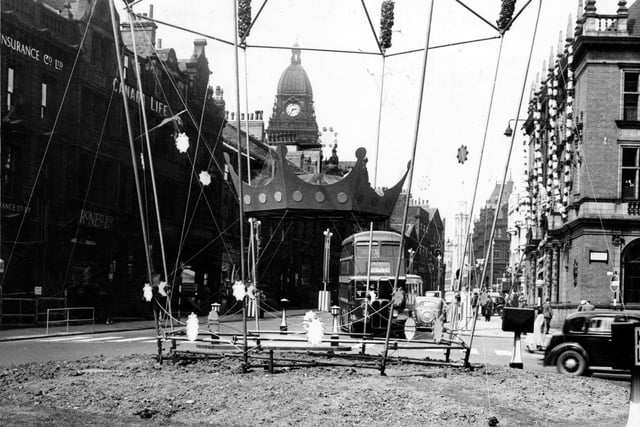 Coronation decorations on East Parade, looking towards The Headrow and Calverley Street. Leeds Town Hall is in the background. A bus on the number 42 route is going to lower Wortley. On the right is the junction with Russell Street. The roundabout in the middle no longer exists.