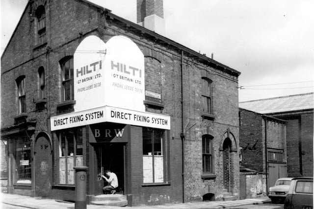 Premises of Hilti (Great Britain) Ltd. Direct Fixing System. The letters BRW are above the door. It would appear that renovations are taking place, a man is fixing the door and the windows are partially covered with newspaper.