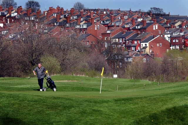 A golfer strides out onto one of the greens against the backdrop of the streets of Kirkstall at Leeds City Golf in April 2003.