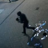 A suspected burglar flees the scene of a theft, dropping trading cards on the pavement