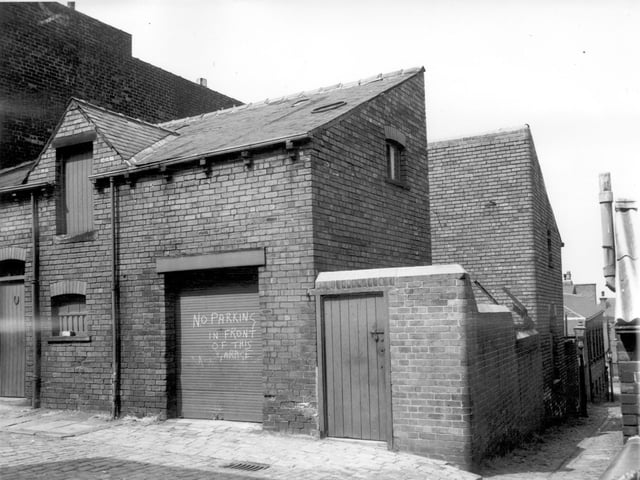 Back Malvern Road off St Luke's Road. A garage door can be seen with a sign chalked on it saying 'No parking in front of this garage'. Far right can be seen a gas lit alley which runs almost parallel to St Luke's Road.