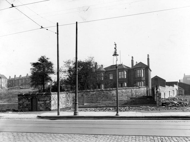 Part of Armley Road, showing tramlines, overhead cables, ornamental wrought iron street lamp, and large house with high wall around garden. Pictured in September 1937.