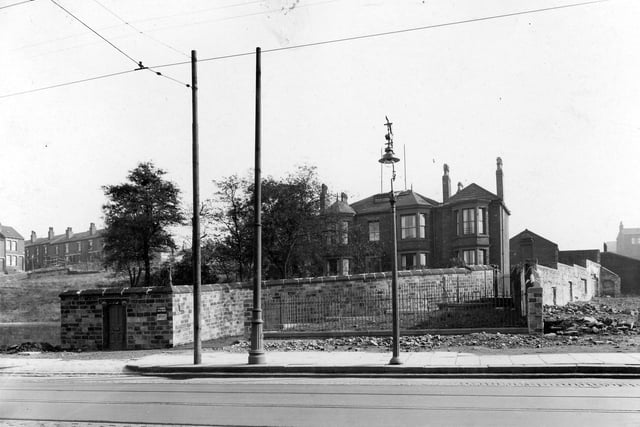 Part of Armley Road, showing tramlines, overhead cables, ornamental wrought iron street lamp, and large house with high wall around garden. Pictured in September 1937.