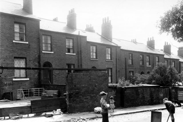 Boys are playing cricket with bat and wicket. On the right is a Craven milk delivery float in Caledonian Street in July 1960.