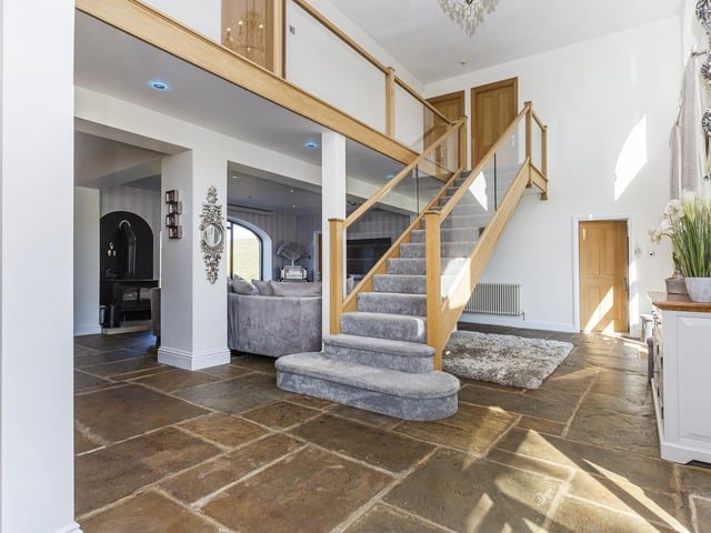 An oak and glazed staircase leads up from the ground floor's open plan hallway.