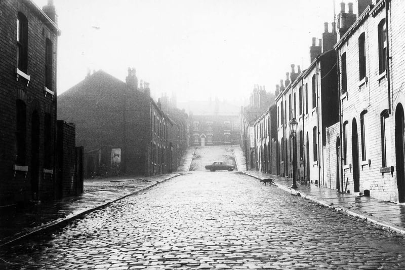 Looking south-west along Servia Mount from Cambridge Road towards Servia Hill in 1970. Servia Road crosses the street in between at the point where a car is seen in the background. These streets are in the process of demolition as part of a large scale clearance of terraced housing in the area; some houses on the left have already been cleared.
