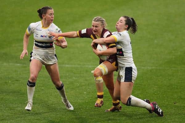 Bella Sykes, of Huddersfield, is tackled by Rhinos' Izzy Northrop during Leeds' win at John Smith's Stadium in April. Picture by John Clifton/SWpix.com.