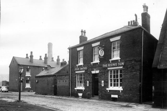 The Rising Sun pub on Ramsden Street in March 1965. In the background is a chimney which belongs to W. and A. Boyd, cloth finishers and carbonisers at Victoria Mills on Domestic Street. On the left is the entrance to Sowerby Street then the side of a garage.