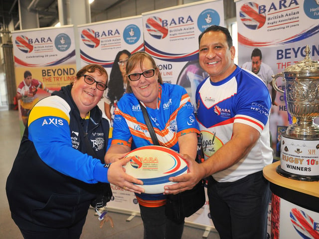Former Leeds player Ikram Butt, co-director and founder of the British Asian Rugby Association at their heritage stand with fans Rhinos Sammy Lynch, of Beeston and Fiona Magee, of Bell Isle.