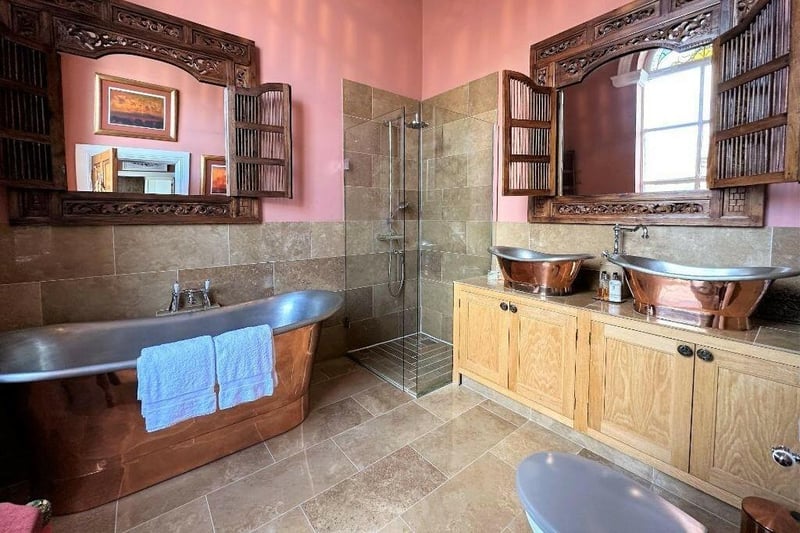 This en suite to the master bedroom has a roll top copper bath and double sinks crafted out of fossilized wood.