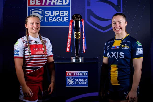 Leeds Rhinos' Ella Donnelly with Izzy Rowe, of Wigan Warriors and the Betfred Women's Super League trophy. Picture by Allan McKenzie/SWpix.com.