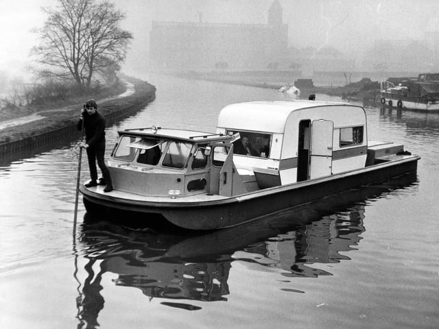 A caravan sets sail in a specially designed boat on the Leeds Liverpool Canal in January 1971. The craft designed to carry a caravan on inland waterways is the brainchild of John Kippax. The 30-year-old, a director of Bradford Boats Services Ltd., had-toyed with the idea of building the craft for several years after caravan owners had booked one of the firm's cruisers for a holiday on the Leeds-Liverpool canal. "They had to leave their caravans at home and I thought it would be a good idea to build a boat with the engine after and the control cabin forward and a deep well in the middle," he said.