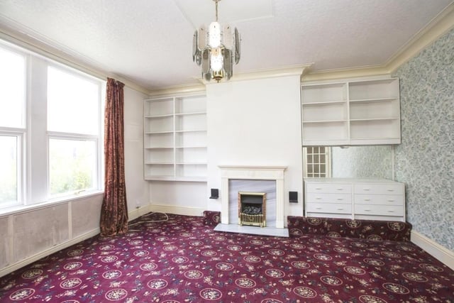 A reception room with a central fireplace and built-in shelving.