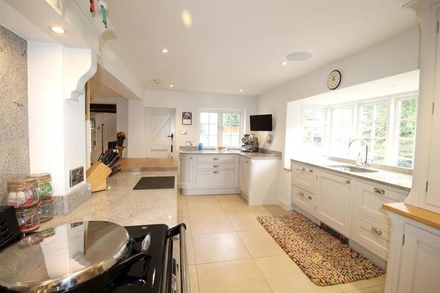 A bright and open plan kitchen with bespoke fitted cabinets, granite and beech worktops, and integrated appliances.