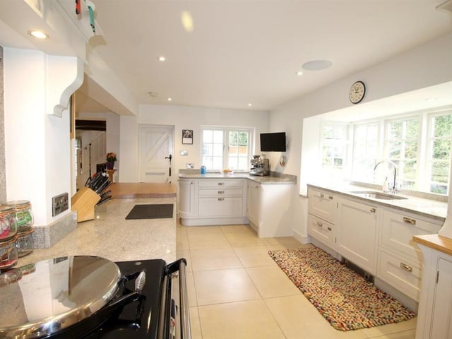 A bright and open plan kitchen with bespoke fitted cabinets, granite and beech worktops, and integrated appliances.