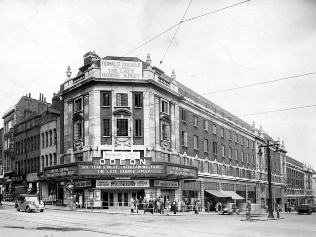 The Odeon Cinema and The Headrow pictured in June 1947. The film showing is 'The late George Apley' and outside there are people meeting, there is a cinema doorman, newspaper sellers and two people talking to a policeman. On New Briggate number 12 Meesons, 14 Model Makers, 16 Mentels, 18a Chemists and 20 Pitman's College, can be seen. The cinema opened as the Paramount in 1932 and became the Odeon in 1940.