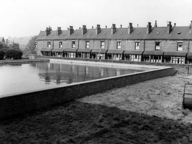 Static water tank which replaced the bowling green of the Leeds Constitutional Club, as a wartime measure. A bowling green roller is visible with a bird sitting on it. Good view of Hill Top Mount which is behind the water tank. Picured in August 1942.