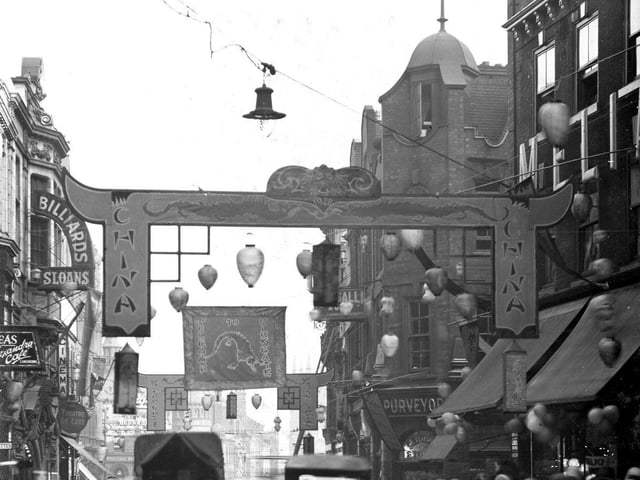 Kirkgate became the Chinatown of Leeds during Civic Week. Pagoda style arches span the street and are decorated with lions and dragons. Lanterns hang across shop fronts and over the street which is busy with people and traffic.