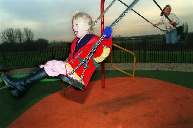 Georgia Della, five, left, and Rebecca Walker, nine, play on swings in the new playground on the Halton Moor estate in December 1998.