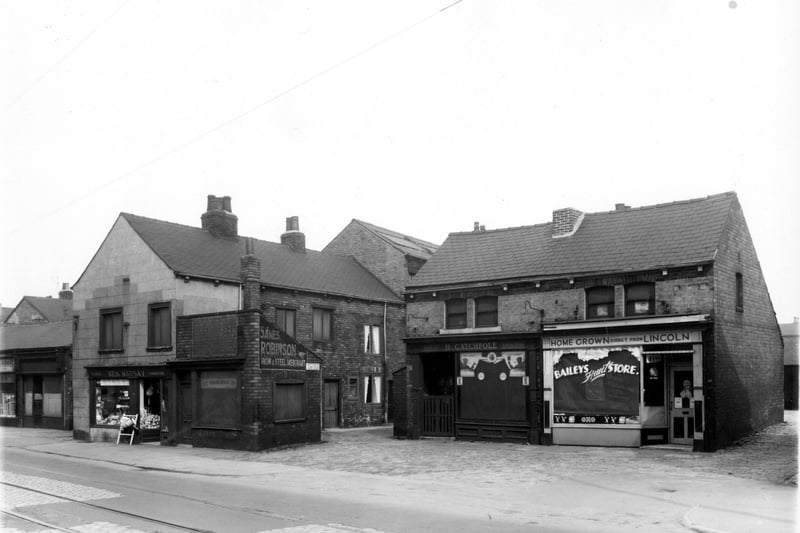 Balm Road in April 1959. On the left is a disused shop which had at one time been a dressmakers. Moving right there is a plumbers shop and another vacant one storey shop which had once been a boot and shoe repairs before being used by a business offering a wedding service according to a sign in the window. Continuing right is one entrance to Carr Fold.