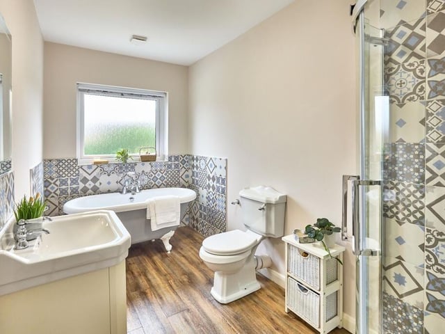 The family bathroom features a freestanding roll-top bath and enclosed corner shower area.