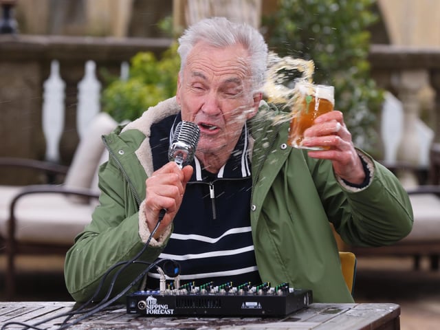 Larry Lamb battling the wind, delivering The Sipping Forecast to help the country navigate unpredictable pub-garden weather this spring.