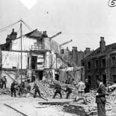 Air raid precaution and rescue personnel simulating a rescue operation. Twelve dummies have been placed in the ruins of the two houses, some of them have been brought out. Here a derrick has been built and is being swung into operation to move heavy debris. The bedford truck has Leeds coat of arms on the door and a sticker on the windscreen.