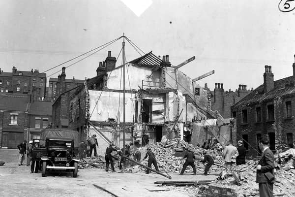 Air raid precaution and rescue personnel simulating a rescue operation. Twelve dummies have been placed in the ruins of the two houses, some of them have been brought out. Here a derrick has been built and is being swung into operation to move heavy debris. The bedford truck has Leeds coat of arms on the door and a sticker on the windscreen.